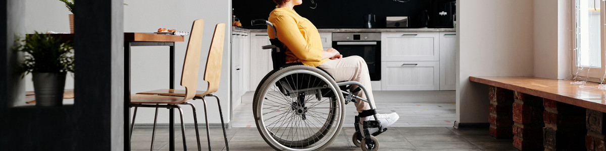 mujer  en silla de ruedas mirando por una ventana
